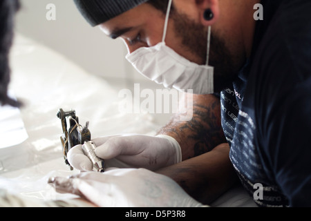 Tattoo artist doing his job. Stock Photo