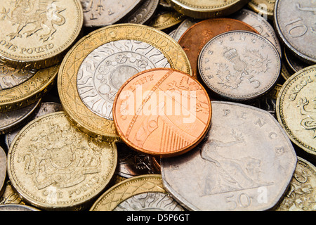 A single British Penny, in the center, and on top of a pile of other current, modern (GBP) coins. Stock Photo