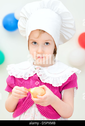 Little girl in chief hat cooking dinner Stock Photo