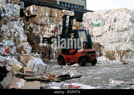 man in fork lift moving bales of waste paper at a recycling plant Stock Photo