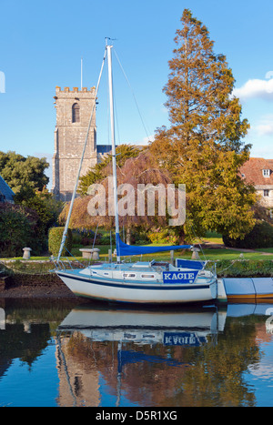 A boat on the river Frome, Wareham, Dorset, England with the Anglo-Saxon church of Lady St. Mary in the background Stock Photo