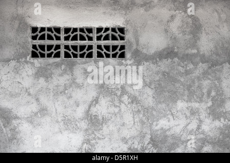 Gray rough grunge concrete wall with a ventilation window Stock Photo