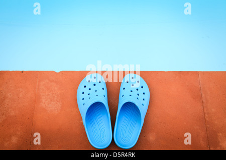 Blue sandals on the poolside of swimming pool Stock Photo