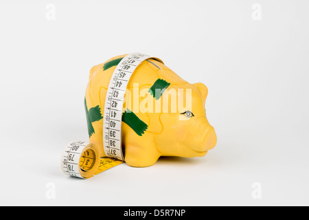 a yellow tape measure wrapped around a piggy bank Stock Photo