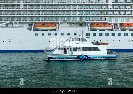 Auckland Harbour Cruiser Discovery III dwarfed by the cruise ship Marina as she docks at the Auckland Ferry Terminal. Stock Photo