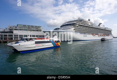 Ferries arriving at the Auckland Ferry Terminal pass the cruise Liner Marina moored in the harbour. Stock Photo