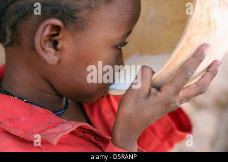 Girl drinks cow's milk from a calabash, Burkina Faso