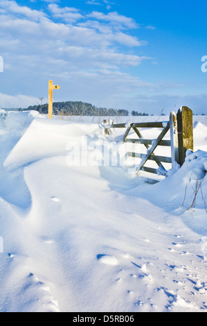 Drifting snow covering a gate, public footpath sign, walls and fields Derbyshire peak district England, GB, UK, EU, Europe Stock Photo