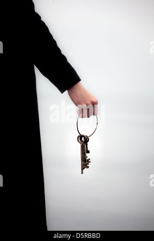 a man in a black coat holding a keyring with old keys Stock Photo