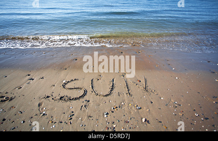 the word sun written in the wet sand  at the beach Stock Photo
