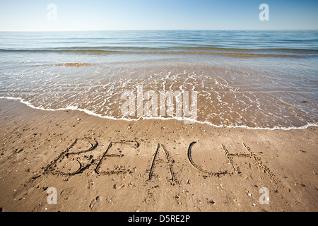The word beach written  in wet sand at the beach Stock Photo