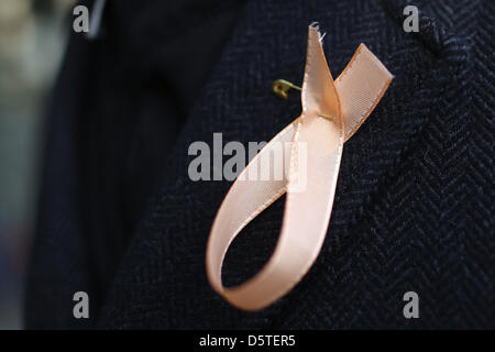 An employee of 'Financial Times Germany' (FTD) wears a salmon-coloured ribbon to express his grief at the publishing house Gruner + Jahr in Hamburg, Germany, 23 November 2012. The publishing house Gruner + Jahr intends to inform employees and work councils on the fait of the business media department of the publisher. A spokesperson of the group announced that one must expect a clo Stock Photo