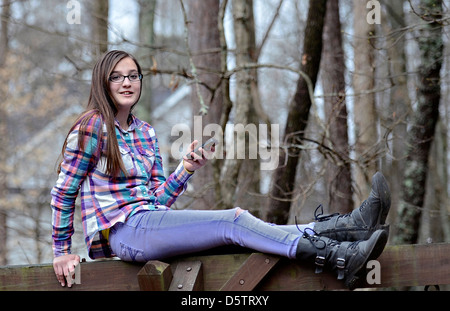 A beautiful teen girl sitting outdoors with her cell phone. Stock Photo