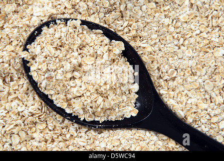 Rolled oats in a black spoon. Abstract food textures. Stock Photo