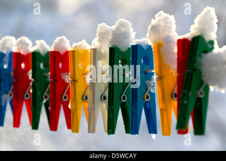 Washing line with a row of colorful pegs covered with snow queued in a row Stock Photo