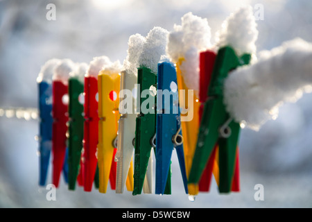 Washing line with a row of colorful pegs covered with snow queued in a row Stock Photo