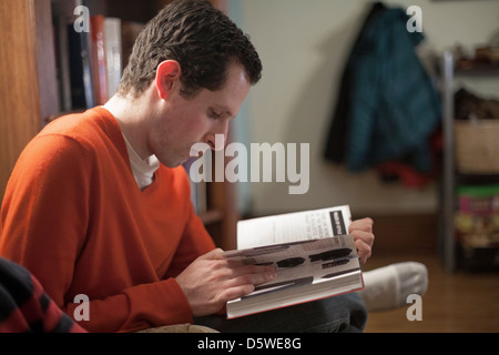 A man reads a book in his living room. Stock Photo