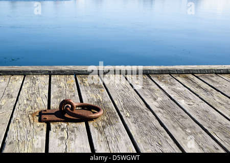 A rusty mooring loop at a wooden pier in sunlight Stock Photo