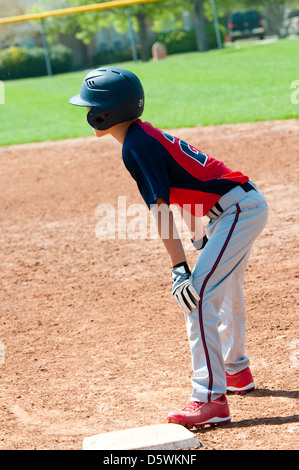 Teen baseball player waiting on first base. Stock Photo