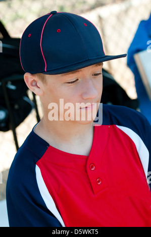 Teen baseball player looking sad in dugout. Stock Photo