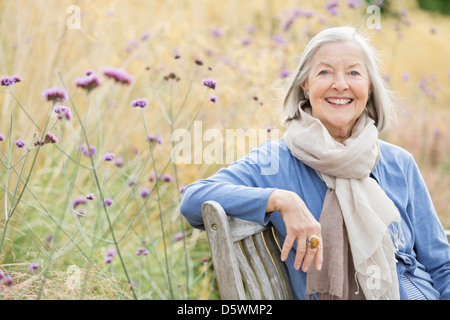 Older woman sitting on park bench Stock Photo