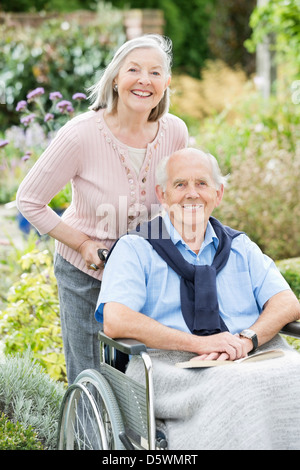 Older woman pushing husband's wheelchair outdoors Stock Photo