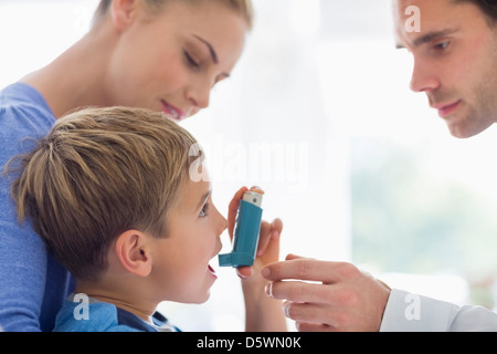 Parents giving son asthma inhaler Stock Photo