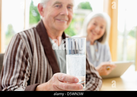 Older man taking medication in water Stock Photo