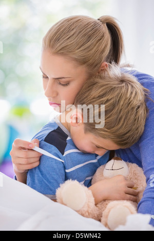 Mother hugging sick son in bed Stock Photo