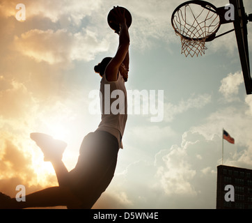Man dunking basketball on court Stock Photo