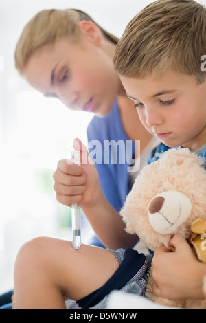 Mother giving son injection in leg Stock Photo