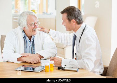 Doctor talking to older patient at house call Stock Photo