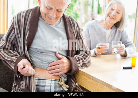 Older man giving himself injection Stock Photo