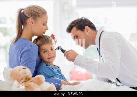 Doctor examining boy's ear at house call Stock Photo