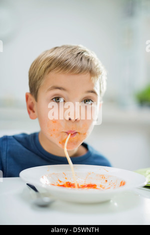 Boy slurping spaghetti at table Stock Photo