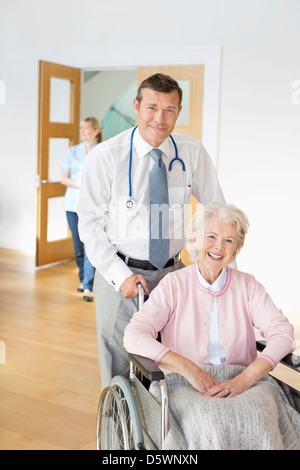 Doctor pushing older patient in wheelchair Stock Photo