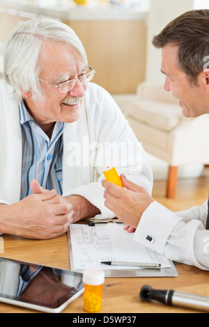 Doctor giving medication to older patient at house call Stock Photo