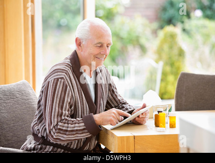 Older man using tablet computer at table Stock Photo