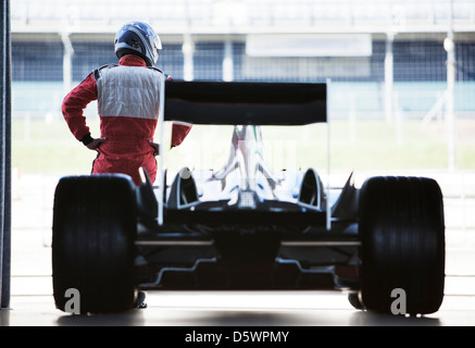 Racer standing with car in garage Stock Photo