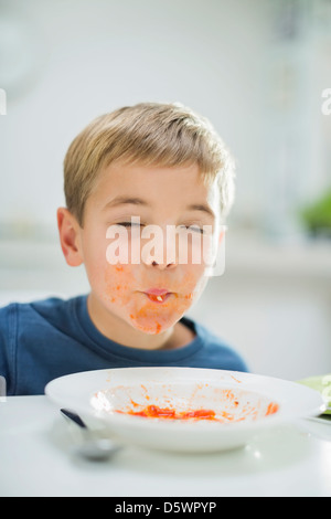 Boy slurping spaghetti at table Stock Photo