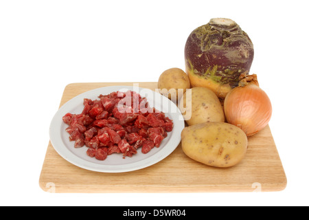 Basic ingredients for the filling of a Cornish pasty, beef,swede,potato and onion on a wooden board isolated against white Stock Photo