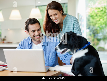 Couple petting dog at table Stock Photo