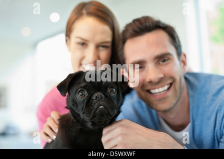 Smiling couple petting dog indoors Stock Photo