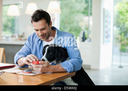 Man feeding dog at kitchen table Stock Photo