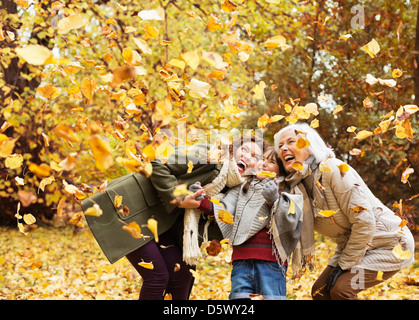 Three generations of women playing in autumn leaves Stock Photo