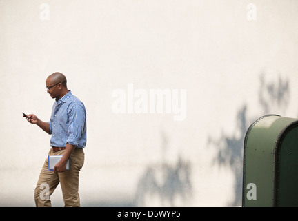 Businessman using cell phone in urban park Stock Photo