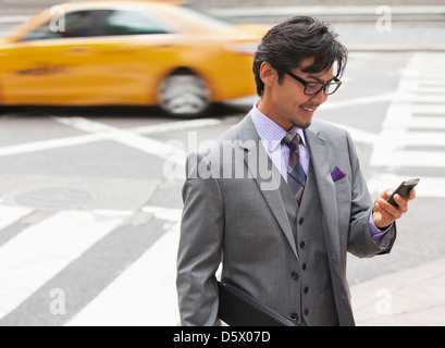 Businessman using cell phone on city street Stock Photo