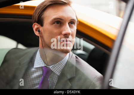 Businessman climbing out of taxi on city street Stock Photo