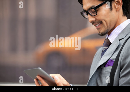 Businessman using tablet computer on city street Stock Photo