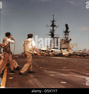 Landing Signal Officers (LSO) observe a LTV A-7 'Corsair II' on board the USS MIDWAY(CV-41). Stock Photo